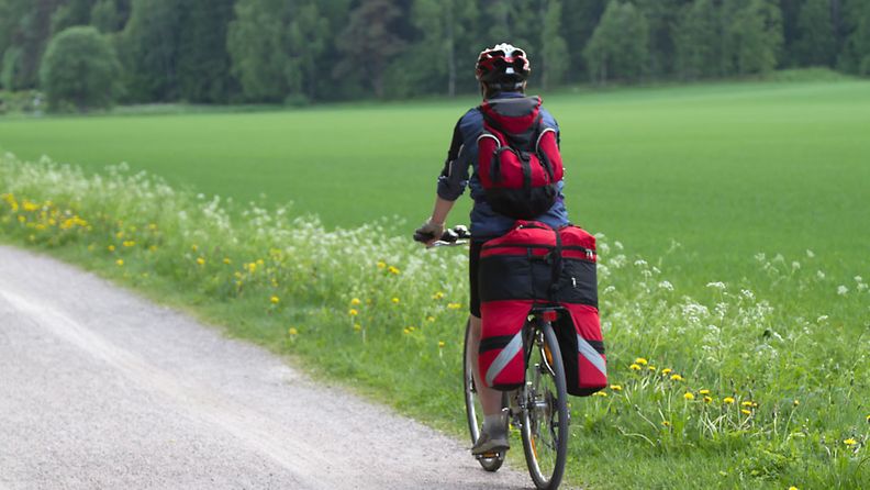 Nainen pyöräilee maaseudulla