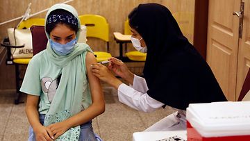 LK 20.11.2021 Opiskelija saa koronarokotteen koulun rokotuskeskuksessa Iranin pääkaupungissa Teheranissa.