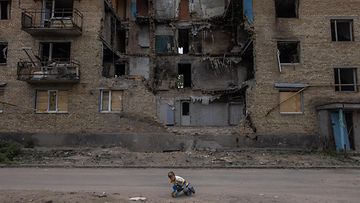 Lapsi leikkii vaurioituneen kerrostalon edessä Kiovan alueella kesäkuussa 2022.